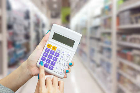 hand holding calculator with blur background of shopping mall market, business financial or shopping conceptの写真素材