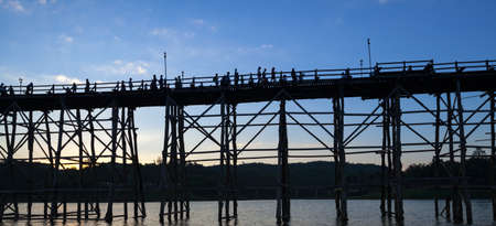silhouette of Utamanusorn Bridge (Mon Bridge), made from wooden for across the river in Sangkhlaburi District, Kanchanaburi Thailand and blue skyの写真素材