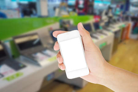 Hand holding smart phone with blur background of shopping IT mall marketの写真素材