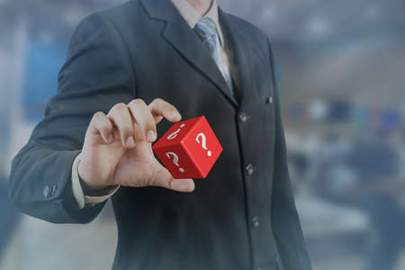 businessman hand and hold red cubic with question markの写真素材