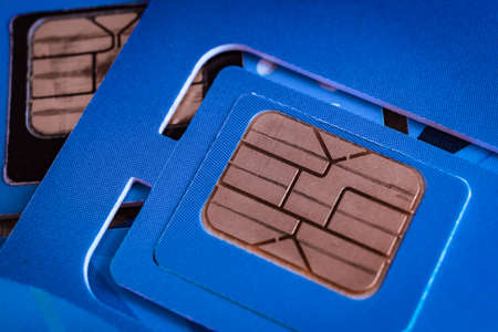 sim card used of mobile smart phone close up macro shot on blue card background, technology concept themeの写真素材