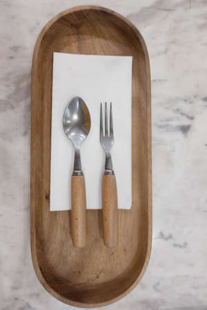 spoon and fork on wooden plate, top viewの写真素材
