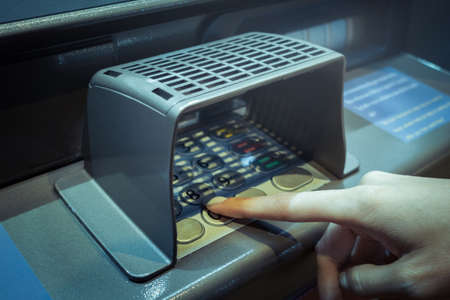 finger point at A.T.M. numpad keypad with guard for protect and use deposit or withdraw money, closeupの写真素材