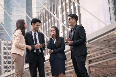 businessmen and women group happy to use smart phone and modern office building backgroundの写真素材