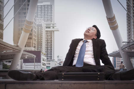 Asian businessman wearing glasses tired and briefcase for working, lay down on the floorの写真素材