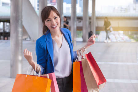 asian woman shopping smile and holding  shopping bag with shopping mall background, consumerism, sale and people online conceptの写真素材