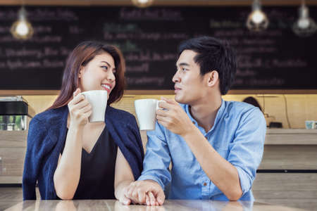 couple having coffee and hold hand in love together in cafeの写真素材