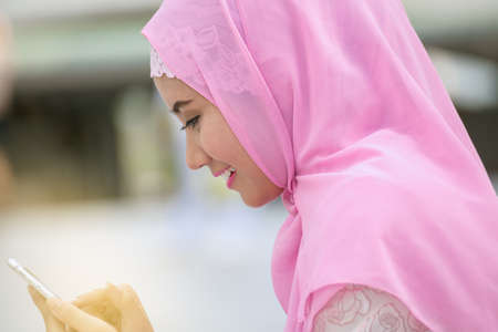 Arabian business woman smiling happy to use cell phone and modern business city backgroundの写真素材