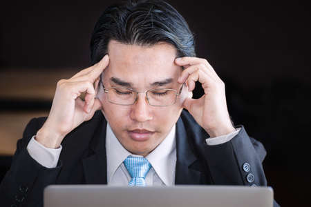 businessman close his eyes and thinking about business on laptop backgroundの写真素材