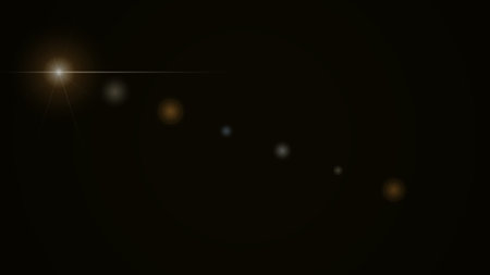 Bright lens flare with scattered light spots creating a dynamic visual effect on a solid black background. Ideal for overlays or creative design elements.の写真素材