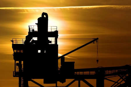 Silhouette of a crane during sunset, on a harbour area. The crane is to be found in Aalborg, Denmarkの写真素材