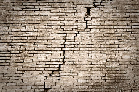 Deep crack in a brick wall - toned imageの写真素材
