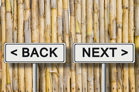 The words "Back and Next" written on a road sign against a fence wattleの写真素材
