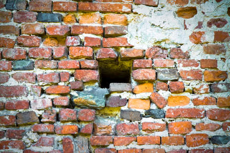 Little hole in an old brick wall - concept imageの写真素材