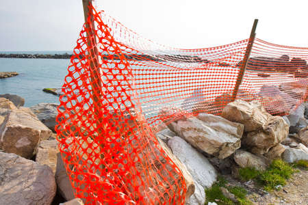Construction site with safety orange grid at the seasideの写真素材