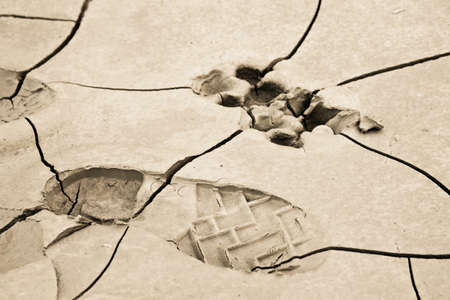 Heavy footprint left on a muddy sand by a male boot. Little vignette effect added.の写真素材