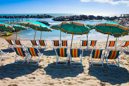 Row of colorful beach umbrellas and chairsの写真素材
