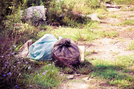 Illegal dumping in the nature; garbage bags left in the nature - toned imageの写真素材