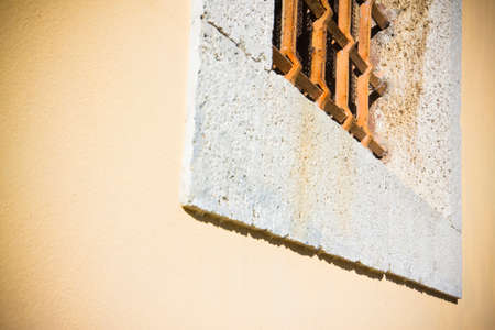 Brick and stone wall with an old rusty grating