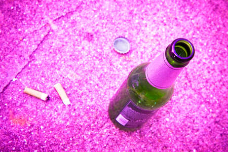 Bottle of beer resting on the ground with three cigarette's butts.
Alcoholism and tobacco addiction concept - toned imageの写真素材