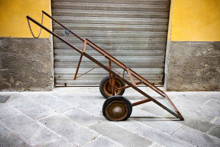 Old metal pushcart against a colored wallの写真素材