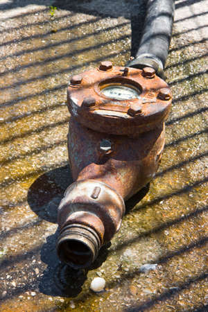 Old and rusty big water meter placed on the ground
