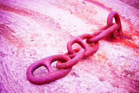 Detail of an old rusty metal chain anchored to a concrete block - toned imageの写真素材