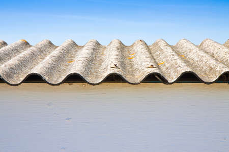 Wooden shack with a dangerous asbestos roof against a blue skyの写真素材