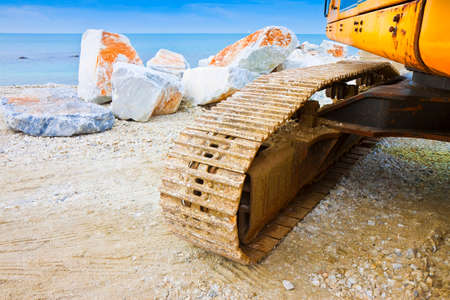 Detail of the track of a digging machine and moving earth at construction site. Diggers on the...