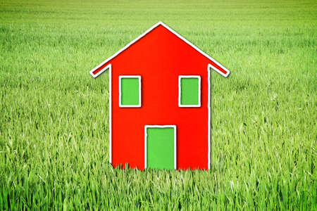 Little red house on green meadow - concept imageの写真素材