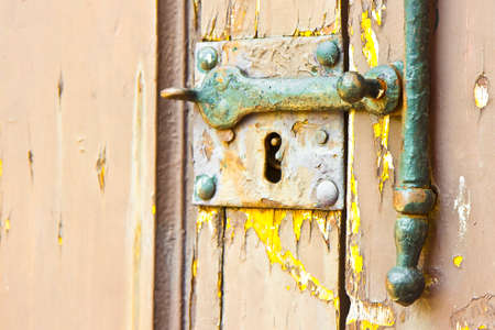 Old wooden door with rusty lock and damaged paintの写真素材