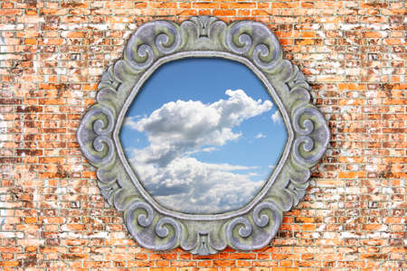 Old carved stone frame with the sky in the middle on brick wall background の写真素材