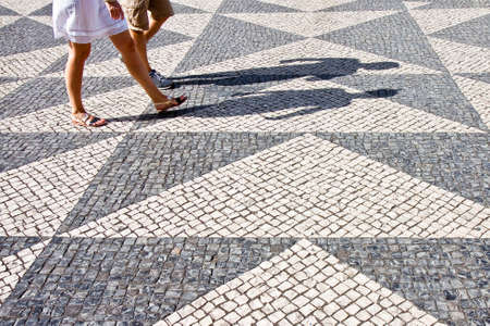 Two people walking in a typical Portuguese street paved in little stone - image with copy spaceの写真素材