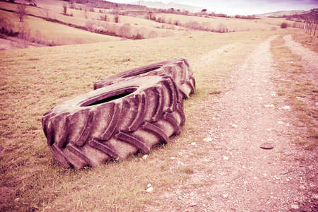 Pair of tires of a big tractor dismantled and left in a Italian country road - toned imageの写真素材