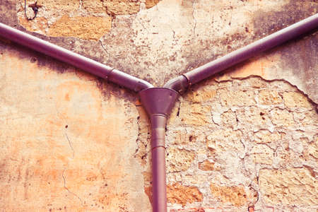 Old copper downpipe against a plaster and stone wall - rainwater recovery concept image -toned imageの写真素材