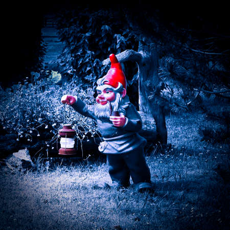 Gnome holding a lantern and smoking a pipe in a blue nightの写真素材