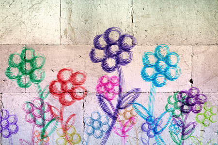 Colored flowers drawn on a white stone wall の写真素材