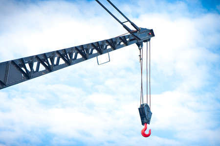 Black tower crane with red hook in a sky backgroundの写真素材