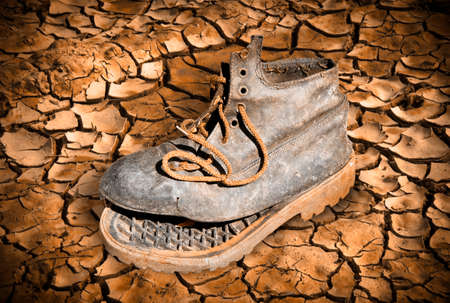 Old broken boot abandoned on a cracked ground - poverty  conceptの写真素材