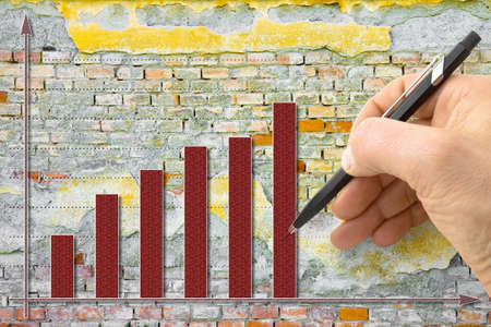 Hand draws a growing graph against a brick wall background - concept image