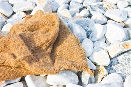 Jute bag left on a white gravel beach