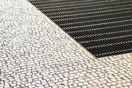 Ventilation iron grid on urban area with stone road - image with copy spaceの素材 [FY310127171079]