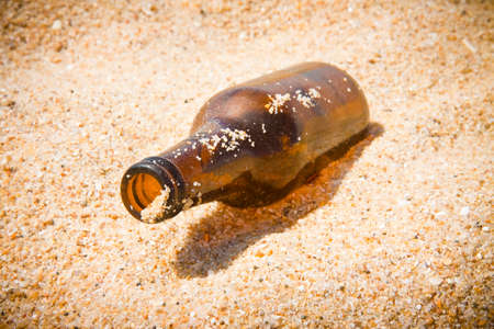 Bottle of beer glass abandoned on the beachの写真素材