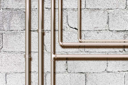 Water and gas metal pipeline in front of a concrete wall.