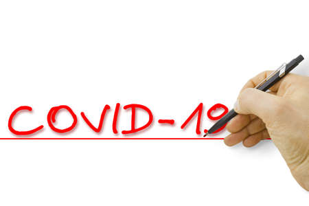 Hand writing coronavirus COVID-19 text on white background - concept image.