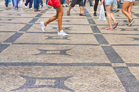 People walking in a typical Portuguese street paved in little stone.の写真素材