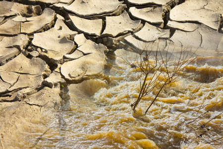 Raging waters and murky after several days of rain versus infertile land burned by the sun - concept...