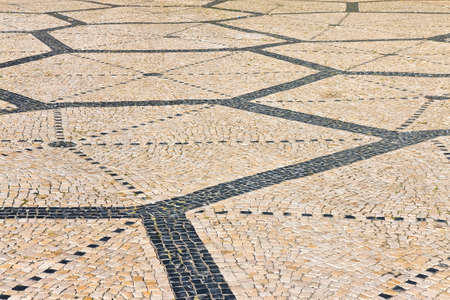 Typical portuguese floor made of small pieces of black and pink stone (Portugal - Europe)の写真素材