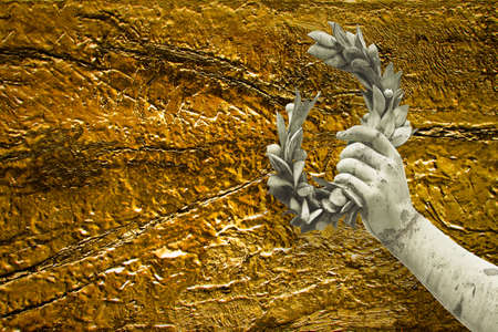 Hand holds a laurel wreath - bronze statue on golden background - Success and fame concept image with copy space.の写真素材