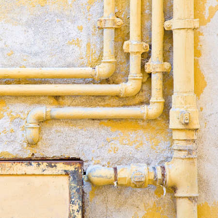 Old domestic protective metal box of water and methane gas against a damaged varnished plaster wall...